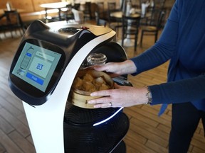 A customer receives a meal delivered by a BellaBot robot at the Noodle Topia restaurant on Monday, March 20, 2023, in Madison Heights, Mich. Many think robot waiters are the solution to the industry’s labor shortages and sales have been growing rapidly in recent years, with tens of thousands now gliding through dining rooms worldwide.