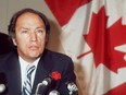 Canadian Prime Minister Pierre Elliott Trudeau, wearing a rose in his buttonhole, addresses media 23 October 1974 in Paris in front of a Canadian flag.
