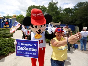 A person wearing a mouse costume takes selfies with supporters of Florida's Republican-backed "Don't Say Gay" bill that bans classroom instruction on sexual orientation and gender identity for many young students gather for a rally outside Walt Disney World in Orlando, Fla.