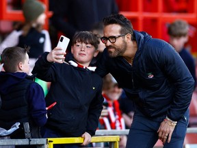 A fan takes a photo with Wrexham co-owner Ryan Reynolds before the match on Monday. April 10.
