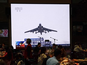 Customers dine near a giant screen broadcasting news footage of aircraft taking part in a combat readiness patrol and 'Joint Sword' exercises around Taiwan, at a restaurant in Beijing, China April 10.