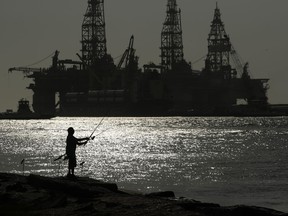 FILE - A man fishes near an oil drilling platform on May 8, 2020, in Port Aransas, Texas. Offshore oil and gas operations in the Gulf of Mexico are releasing far more climate-changing methane than official estimates show, according to a new study published Monday, April 3, 2023.
