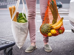 A woman holds bags of groceries.