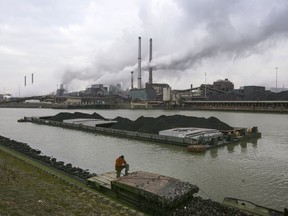 FILE- A worker is seen on a pontoon near the former Corus, and current Tata steel factory, background, in IJmuiden, Netherlands, on Tuesday Jan. 30, 2007. Businesses and local governments in the Netherlands must do more to protect residents who live near large industrial plants against the damaging effects of emissions, an independent report concluded Thursday, Aptil 13, 2023.