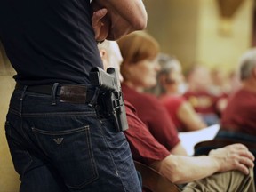 FILE - A Glock handgun is holstered on the side of Kristopher Kranz of Bloomington, Minn., as he listens during public testimony on Aug. 20, 2013, in St. Paul, Minn. A federal court ruling that a Minnesota law prohibiting 18-to-20-year-olds from obtaining permits to carry handguns in public is unconstitutional remained on hold Monday, April 3, 2023, while the state pursues a potential appeal.