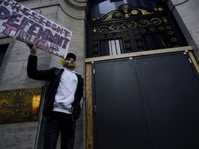 Lucas Camp, of Astoria, holds a sign near Trump Tower, Tuesday, April 4, 2023 in New York. Former President Donald Trump will surrender in Manhattan on Tuesday to face criminal charges stemming from 2016 hush money payments.