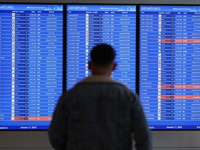 FILE - A traveler looks at a flight board with delays and cancellations at Ronald Reagan Washington National Airport in Arlington, Va., Wednesday, Jan. 11, 2023. Congressional investigators said in a report Friday, April 28, 2023, that an increase in flight cancellations as travel recovered from the pandemic was due mostly to factors that airlines controlled, including cancellations for maintenance issues or lack of a crew.