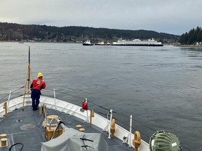 In this photo posted to social media by the U.S. Coast Guard, a crew stands by ready to assist as emergency personnel respond to the Walla Walla passenger ferry, background right, which ran aground near Bainbridge Island west of Seattle, Saturday, April 15, 2023. (U.S. Coast Guard via AP)