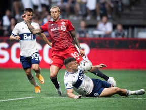 Vancouver Whitecaps' Lucas Cavallini, front right, slides to take the ball away from Toronto FC's Federico Bernardeschi (10) during the first half of the Canadian Championship soccer final, in Vancouver, on Tuesday, July 26, 2022.