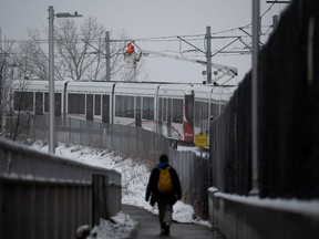 A worker repairs overhead wires on a stalled LRT OC Transpo train near Lees Ave., station in Ottawa, on Friday, Jan. 6, 2023. A severe ice storm that hit Ottawa on Wednesday night has shutdown the light rail transit system due a power outage and has left passengers stuck aboard the train.