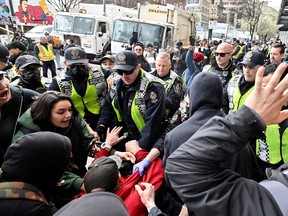 Vancouver Police push back protesters as city staff remove makeshift structures and tents belonging to people living in an encampment along East Hastings Street in the Downtown Eastside, in Vancouver, B.C., April 5, 2023.