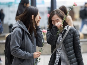 Two women bring flowers as people gather in Toronto's Mel Lastman Square on Tuesday, April 23, 2019 to commemorate a van attack which left 10 people dead. An event commemorating the anniversary of Toronto's attack will be held in the north-end community where the deadly attack took place five years ago today.