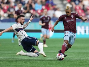 Vancouver Whitecaps' Tristan Blackmon, left, dives to take the ball away from Colorado Rapids' Michael Barrios during the first half of an MLS soccer game in Vancouver, on Saturday, April 29, 2023.