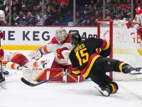 Calgary Flames goalie Jacob Markstrom, back centre, stops Vancouver Canucks' Sheldon Dries (15) during the second period of an NHL hockey game in Vancouver, on Saturday, April 8, 2023.