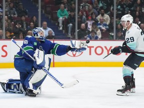 Vancouver Canucks goalie Collin Delia, left reaches for the puck with his glove as Seattle Kraken's Vince Dunn watches during the second period of an NHL hockey game in Vancouver, on Tuesday, April 4, 2023.