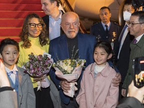 In this photo released by Xinhua News Agency, Brazilian President Luiz Inacio Lula da Silva, center, and first lady Rosangela Silva, second left, receive flowers presented by children from the Shanghai Children's Palace of the China Welfare Institute upon arrival in Shanghai, China on Wednesday, April 12, 2023. Lula was in the Chinese financial hub of Shanghai on Thursday in a bid to boost ties with the South American giant's biggest trade partner and win political support for attempts to mediate the conflict in Ukraine.