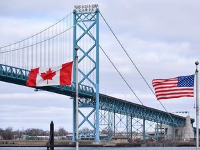 Canadian and American flags fly near the Ambassador Bridge at the Canada-U.S. border crossing in Windsor. (CP Photo)