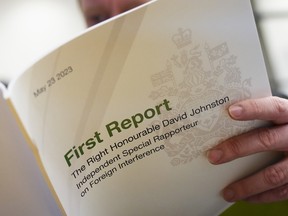 A reporter looks over David Johnston's first report on foreign interference on May 23, 2023. Johnston recommended that public hearings be held on the issue, rather than a public inquiry.