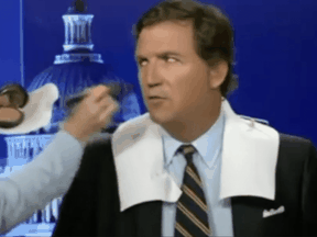 A screen shot of a video in which Tucker Carlson, having his nose powdered, asks about nose-powdering.