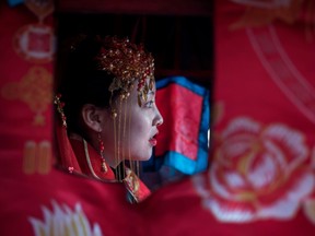 A Chinese woman dressed like a traditional bride, attends a wedding performance on Feb. 16, 2018.