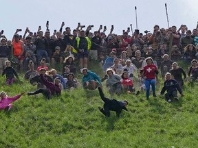 Participants compete in the women’s downhill race during the Cheese Rolling contest