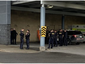 Police officers gather at the Ottawa Hospital Thursday after three OPP were shot, one of them fatally, in the town of Bourget.