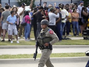 A law enforcement officer walks as people are evacuated from a shopping center where a shooting occured, May 6, in Allen, Texas.