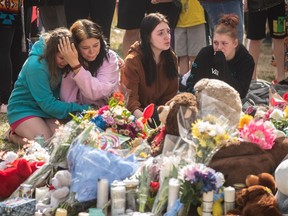 Family and friends console each other at a vigil for a mother and an 11-year-old child who were killed outside a school in Edmonton on Saturday May 6, 2023. Police say the suspect in a fatal double stabbing outside an Edmonton school has a history of mental health concerns and has been charged multiple times in the last decade with assaulting minors.