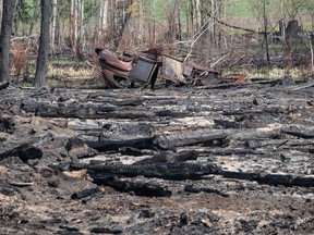 An old car lies burnt in a wooded area where recent wildfires have damaged the land, in Drayton Valley, Alta. on Wednesday, May 17, 2023. Officials in Alberta say there has been significant progress in the fight against wildfires in the province due to rain, cooler weather, and the efforts of firefighters.
