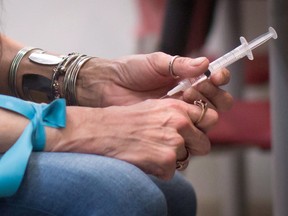 Close-up of a woman's hands as she prepares to inject opioids at a consumption site.