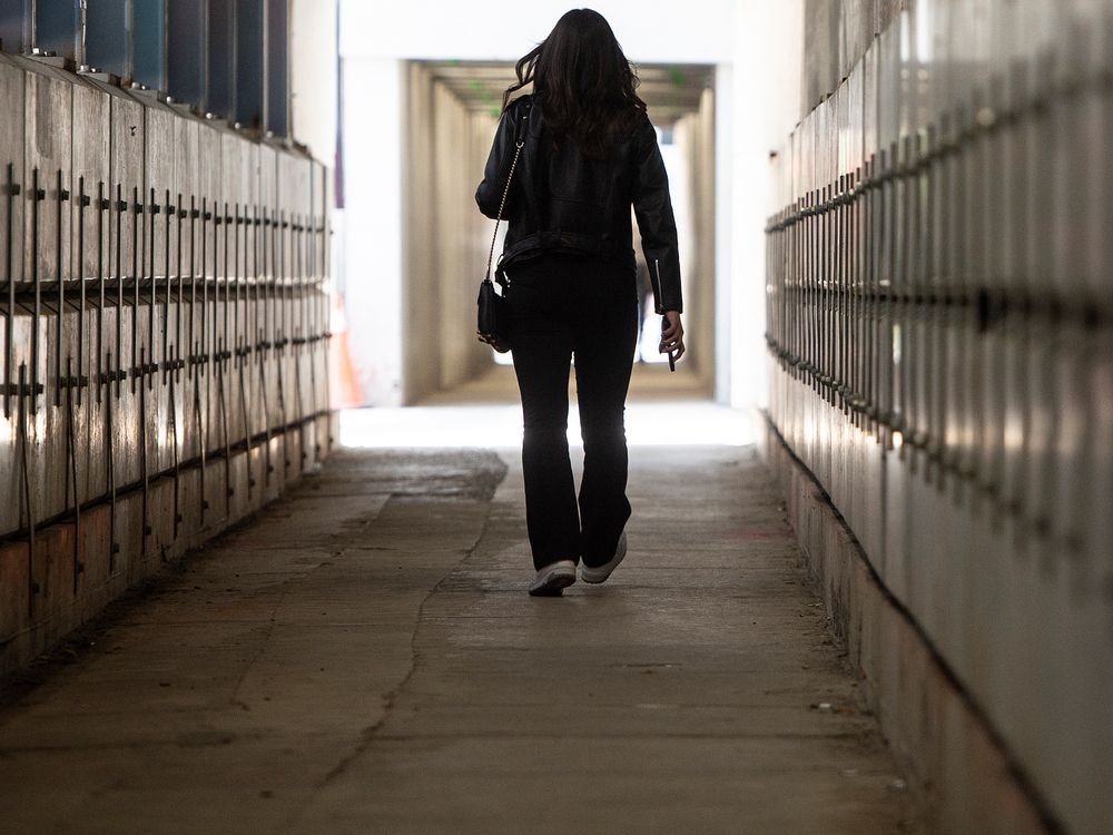 A pedestrian walks through a construction tunnel on Toronto's King Street West.