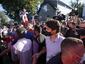Liberal Leader Justin Trudeau is escorted by his RCMP security detail as protesters shout and throw gravel while leaving a campaign stop at a local micro brewery during the Canadian federal election campaign in London Ont., on Monday, September 6, 2021.