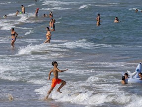 FILE - People cool off on Puerto de Sagunto beach in Spain, Tuesday, Aug. 16, 2022. Summer is often a time of having fun, going on vacation and being carefree. But with inflation, layoffs and a looming recession, you may be questioning the financial impact of your summer plans or they suddenly have become out of reach.