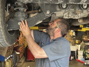 Mechanic Jon Guthrie inspects the underside of a 2014 Honda Ridgeline pickup truck at Japanese Auto Professional Service in Ann Arbor, Michigan. People are keeping their vehicles longer due to shortages of new ones and high prices. That drove the average U.S. vehicle age up to a record 12.5 years in 2022, according to S&P Global Mobility.