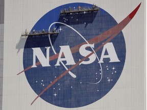 FILE - Workers on scaffolding repaint the NASA logo near the top of the Vehicle Assembly Building at the Kennedy Space Center in Cape Canaveral, Fla., May 20, 2020.