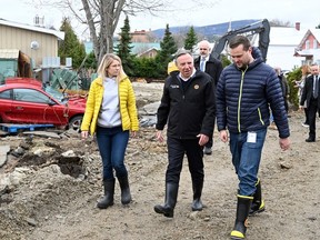 Quebec Premier François Legault chat with Baie-St-Paul mayor Michael Pilote as they tour the site of a major spring flood, Wednesday, May 3, 2023 in Baie-Saint-Paul. Local MNA Kariane Bourassa, left, looks on.