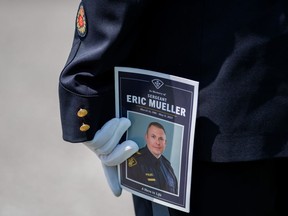 A member of the Ontario Provincial Police holds a program during the funeral of Ontario Provincial Police Sgt. Eric Mueller in Ottawa, on Thursday, May 18, 2023. Sgt. Mueller was killed in the line of duty while responding to call on May 11 in the village of Bourget, Ont. The lawyers for a man accused of killing the Ontario Provincial Police officer and injuring two others are disputing the characterization of the shooting as an ambush.