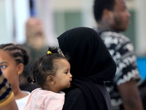 A woman carries a child as people fleeing conflict in Sudan arrive at an airport in Abu Dhabi after an evacuation flight, on April 29, 2023.