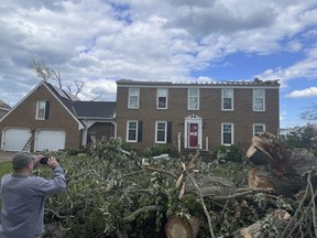 A man photographs a home damaged by a tornado in Virginia Beach, Va., on Monday May 1, 2023.