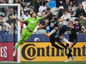 Vancouver Whitecaps' Ranko Veselinovic, second right, heads the ball wide of the goal behind Minnesota United goalkeeper Dayne St. Clair (97) as Kemar Lawrence (92) and Robin Lod, right, defend during the first half of an MLS soccer match in Vancouver, B.C., Saturday, May 6, 2023.