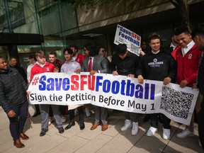 Simon Fraser University football team players hold a banner after attending a hearing at B.C. Supreme Court, in Vancouver, on Monday, May 1, 2023.The Simon Fraser Football Alumni Society outlined details Friday of a proposal it sent to the school regarding the future of its football program.THE CANADIAN PRESS/Darryl Dyck