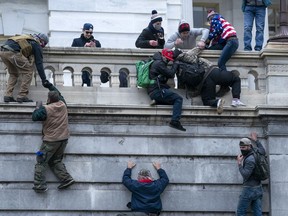 FILE - Rioters loyal to President Donald Trump climb the west wall of the the U.S. Capitol, Jan. 6, 2021, in Washington.