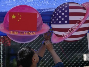 A vendor sets up foods and beverages at a booth displaying planets shaped of China and American flags during a Spring Carnival in Beijing on May 13, 2023. Hong Kong's leader on Tuesday, May 16 said the sentencing on spying charges of a U.S. citizen in China, who was also a permanent resident of the semi-autonomous city, illustrated that the territory should "stay vigilant to national security risks hidden in society."
