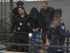 A suspect is escorted by police outside the Vladislav Ribnikar school in Belgrade, Serbia, Wednesday, May 3, 2023. Serbian police say a teenage boy opened fire at a school in central Belgrade, killing several people and injuring several more. (AP Photo)