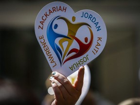 A family member of five slain students holds a heart sign with their names on it following a court decision in Calgary, Alta., Wednesday, May 25, 2016. Alberta's highest court is being asked to overturn a review board decision on the stabbing deaths of five young people at a Calgary house party that confined a man to a supervised Edmonton group home.