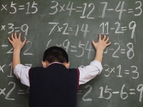 Schoolboy in front of blackboard with hands on chalkboard