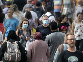 Two people wearing masks while walking in a crowd.