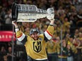A Las Vegas Knights player carries the Stanley Cup over his head.