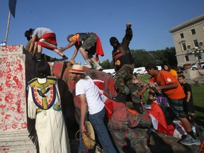 Protesters celebrate atop a destroyed 100-year-old statue of Queen Victoria pulled down in Winnipeg on Canada Day 2021.