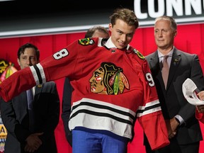 Chicago Blackhawks first round draft pick Connor Bedard puts on his jersey after being picked by the team during the first round of the NHL hockey draft, Wednesday, June 28, 2023, in Nashville, Tenn.